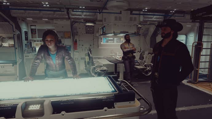 Sarah Morgan and Sam Coe stand around a table on the player’s ship in Starfield.