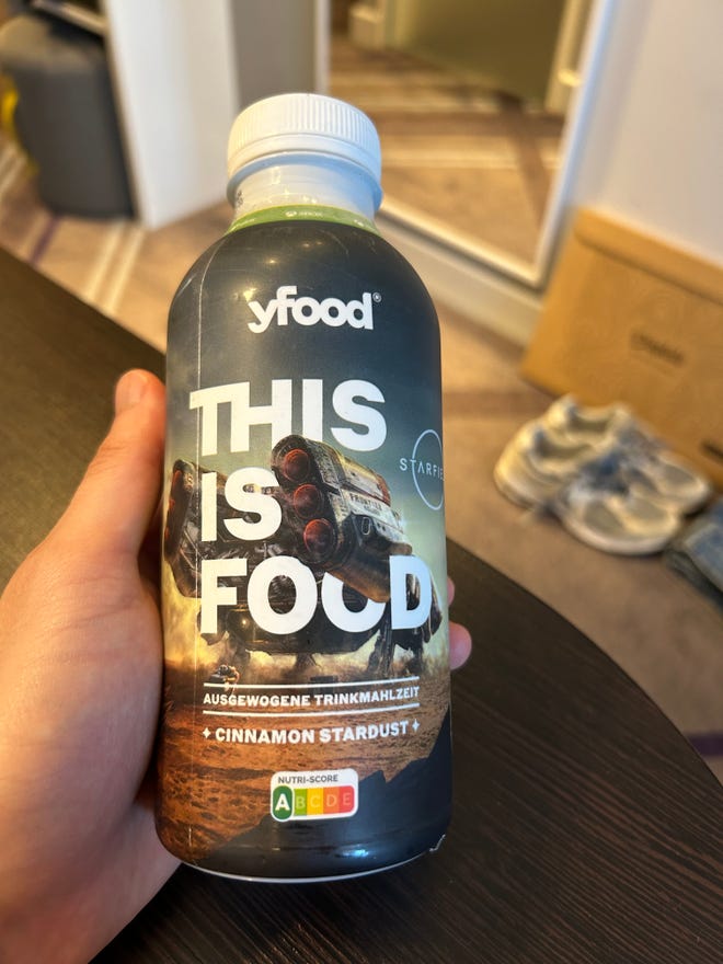 A hand holds up Starfield’s meal drink, flavoured cinnamon stardust.