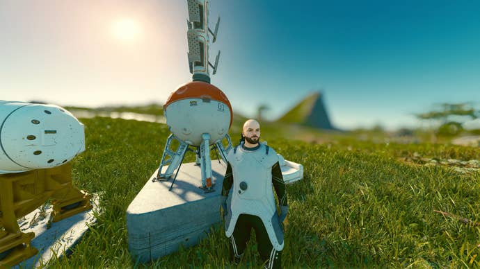 A player in Starfield stands next to the beginnings of an outpost on a green grassy landscape.