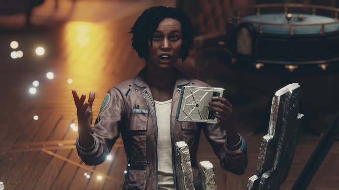 Noel holds a device and gestures while speaking towards the camera in Starfield.