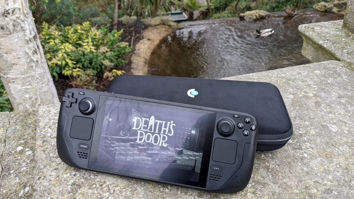 The Steam Deck and its case on a wall next to a pond.