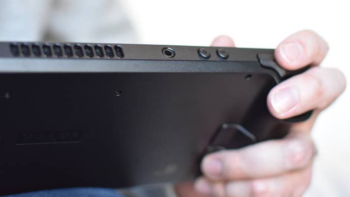 A Steam Deck with the user’s fingers on the shoulder and rear buttons.