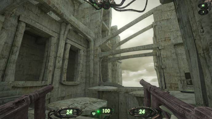 The player holds two machine guns while looking at a concrete city with brutalist architecture.