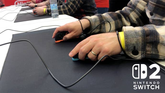 A photograph showing Tom Phillips holding and playing with the Nintendo Switch 2 Joy-Con in their mouse configuration, on a desk, using a mouse mat.