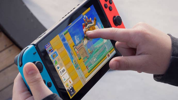 A Switch promotional photo showing an unseen person poking their console’s touchscreen with their finger.