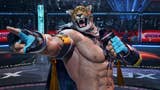 Tekken 8 King - a man wearing a lion mask, a cape, and fingerless gloves holding a microphone in one hand and pointing to the crowd with the other. He is stood inside a wrestling cage