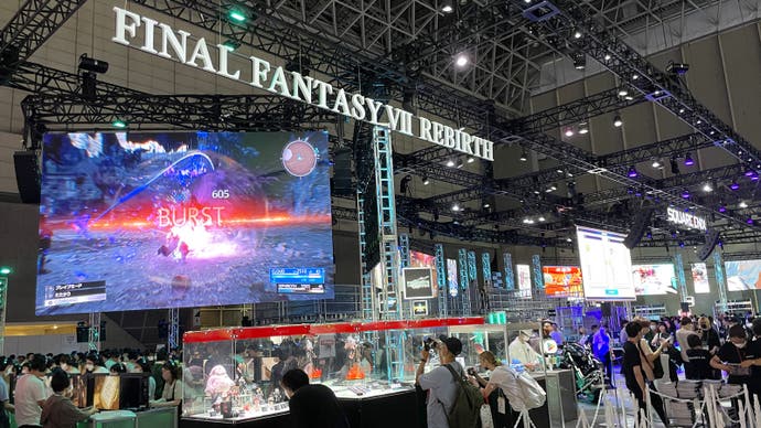 The Final Fantasy stand at Tokyo Game Show, where a large screen hangs from the ceiling above merch in glass cases.
