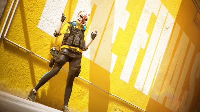 Promo image for The Finals showing a player character in a cat-like mask doing the double ‘finger guns’ pose against a yellow background