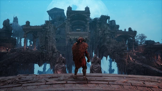 The subordinate wears a reddish cape and stands atop a level looking astatine immoderate ruins.