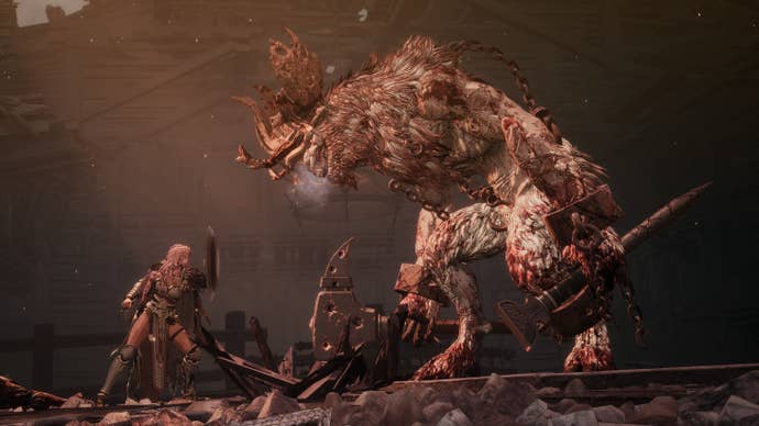 A huge demon stares down at a woman with a shield.