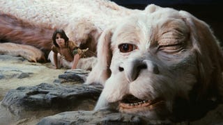 A large, furry, dragon-like creature is resting on a rock, a boy with long-ish hair crouched next to him in The Neverending Story.