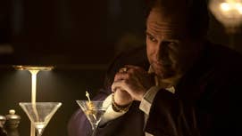 Colin Farrell as The Penguin in the character's titular show, sat at a table in low light, a martini in front of him.