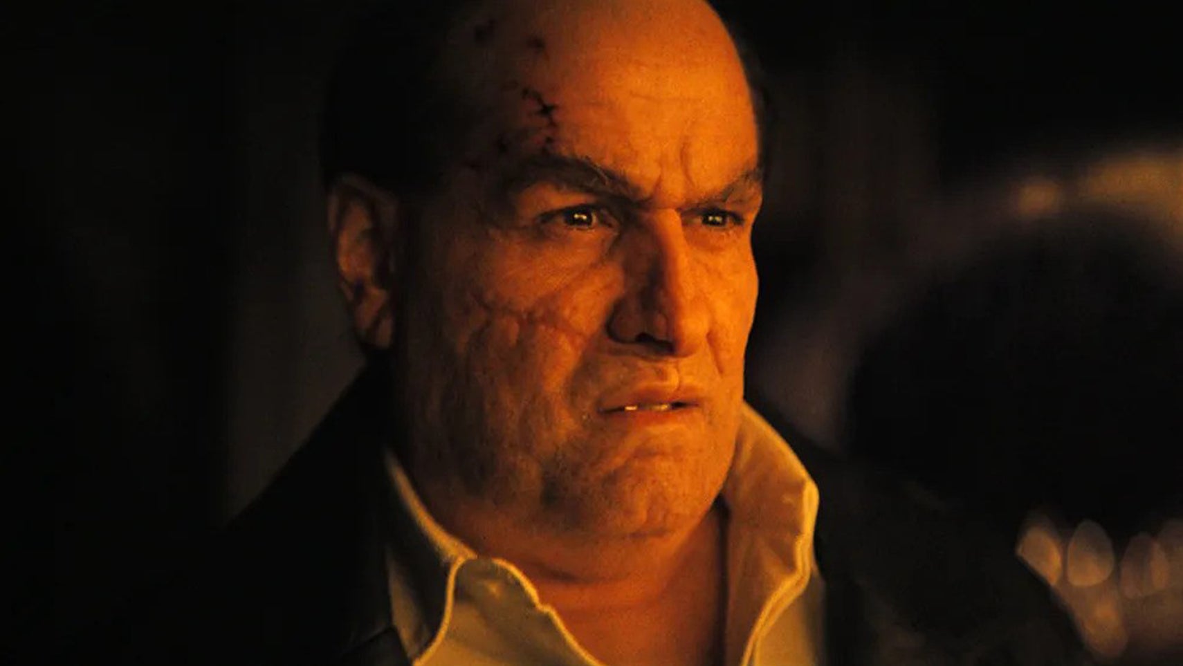 Colin Farrell as Oswald Cobblepot in The Penguin, a warm light is hitting his face, he's looking slightly disgruntled about something. - 1