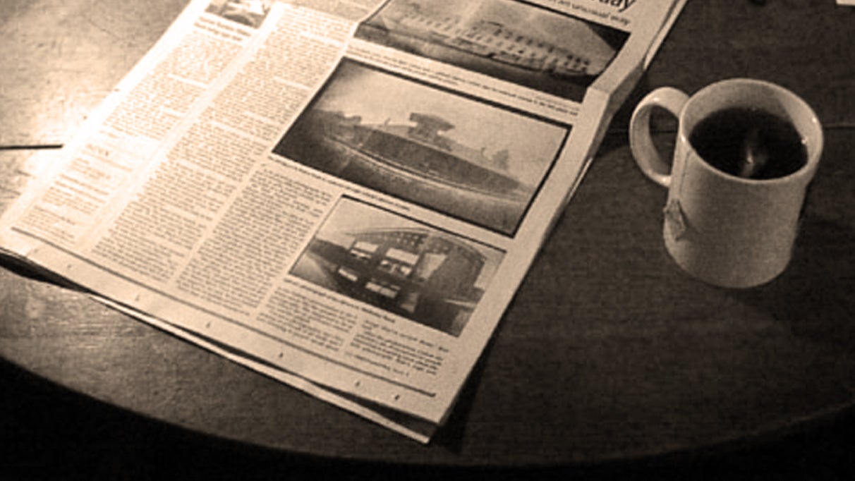 A plain white mug of black tea or coffee, next to a broadsheet paper on a table, in black and white. It's the header for Sunday Papers! - 1