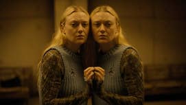 Dakota Fanning in The Watchers is pressed up against a mirror, looking at something offscreen, she likes tired and concerned.