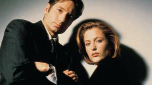 Fox Mulder and Dana Scully from The X-Files stood in front of a blank background looking into the camera.
