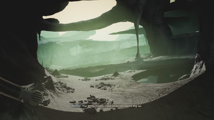 A screenshot from The Invincible, showing a rocky and caved planetary surface bathed in a greenish mist and glow.