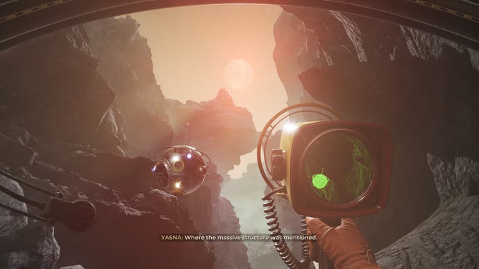 A screenshot from The Invincible. It's a first-person view from a rocky canyon as the boiling orange sun above goes down. The player holds a scanning device that looks like an old, small, film recorder. A basketball-sized, metal probe hovers nearby.