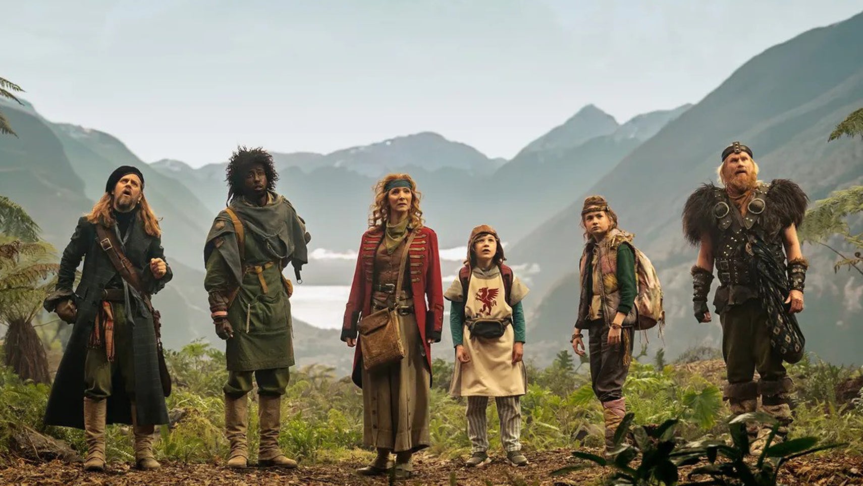 The main cast of the Time Bandits TV series stood in a line in a mountainous area all looking at something offscreen. - 1