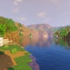 A screenshot of a river in Minecraft, with some trees on either side of the bank and a hill in the distance, taken using TME shaders.