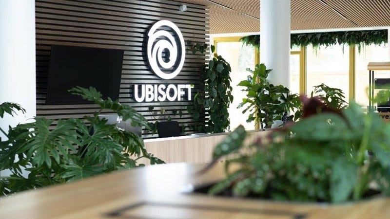 A picture of a lobby in an Ubisoft building with green plants and the company logo