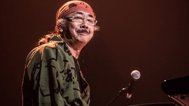Nobuo Uematsu sat at piano with microphone in red bandana