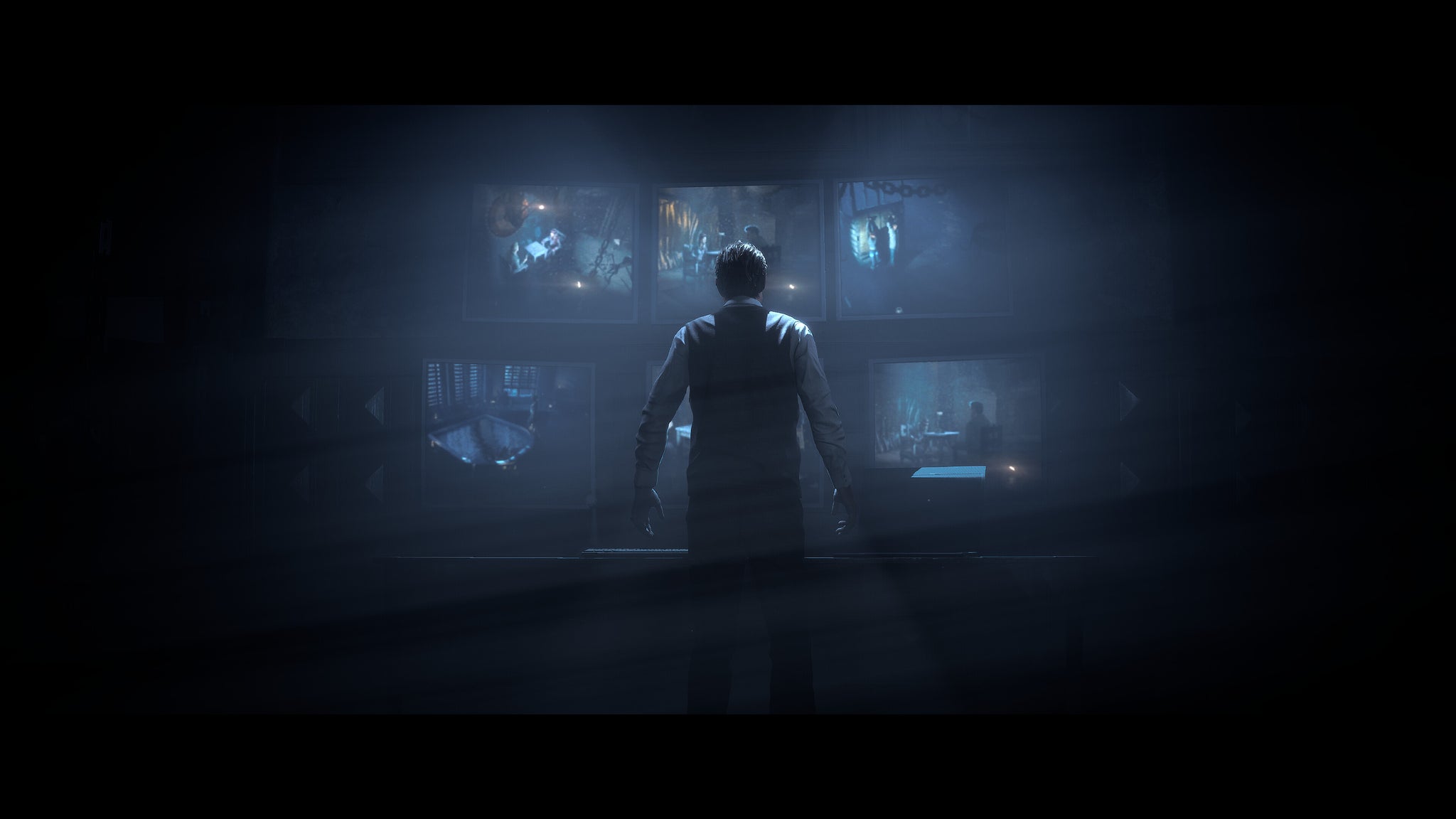 Doctor Hill stands silhouetted against a bank of monitor screens showing camera feeds from various rooms inside the lodge. - 6