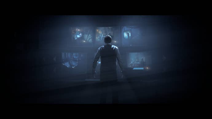 Doctor Hill stands silhouetted against a bank of monitor screens showing camera feeds from various rooms inside the lodge.