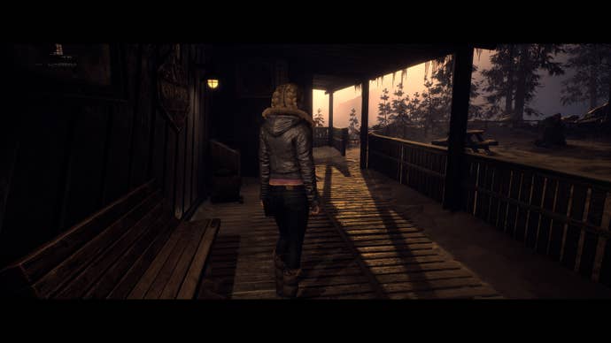 Jess stands in the shelter of the cable car station and watches the sunset over the mountains.