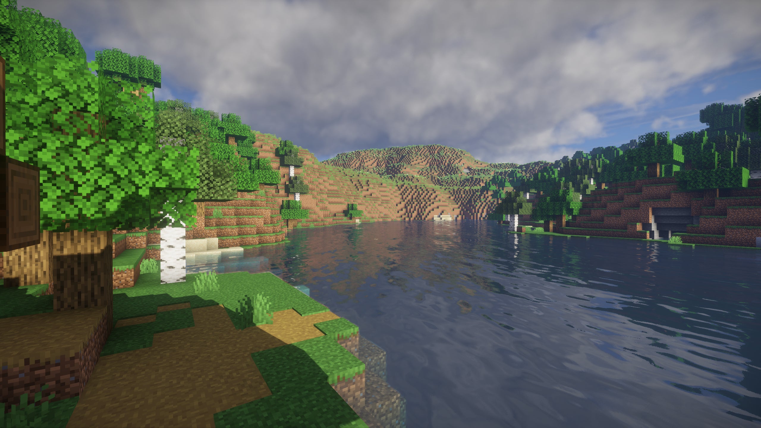 A screenshot of a river in Minecraft, with some trees on either side of the bank and a hill in the distance, taken using UShader shaders.