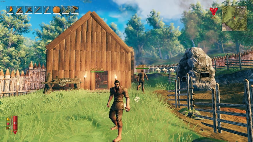 My viking, wearing a ragged tunic and pants stands outside a wooden house.