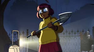 The titular Velma is holding a shovel in a graveyard, a flashlight lighting her up from the side, she looks slightly scared.
