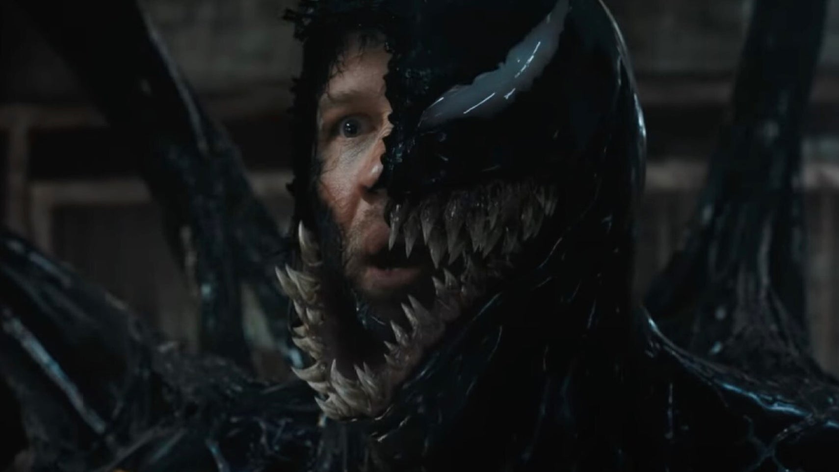 A still from Venom: The Last Dance of Tom Hardy as Eddie Brock, half of his face visible underneath Venom. - 1