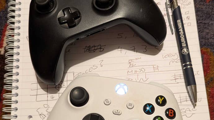 A photograph taken by Eurogamer’s Victoria showing two Xbox controllers on a notepad that has some puzzle solutions written on it. A Eurogamer branded pen is artfully included in the tableau.