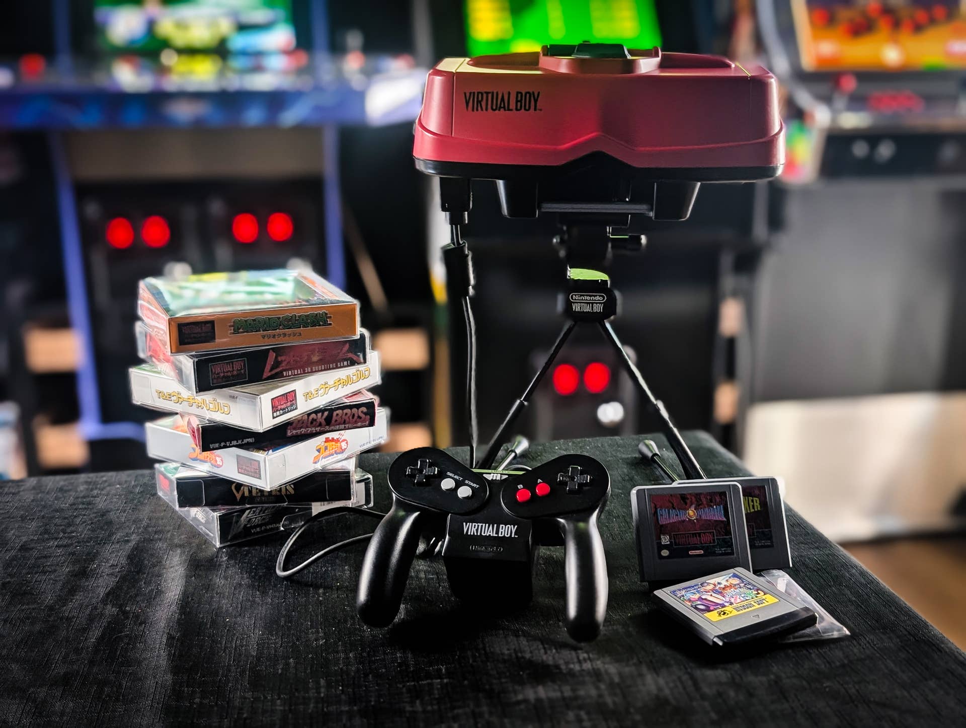A stack of games, a pad, and the Virtual Boy unit itself, photographed near-field in an arcade setting