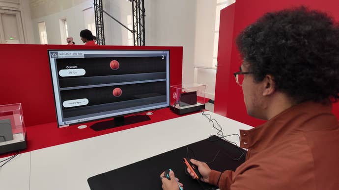 A man in a brown coat and black hair plays a game split into two horizontal screens against a red backdrop.