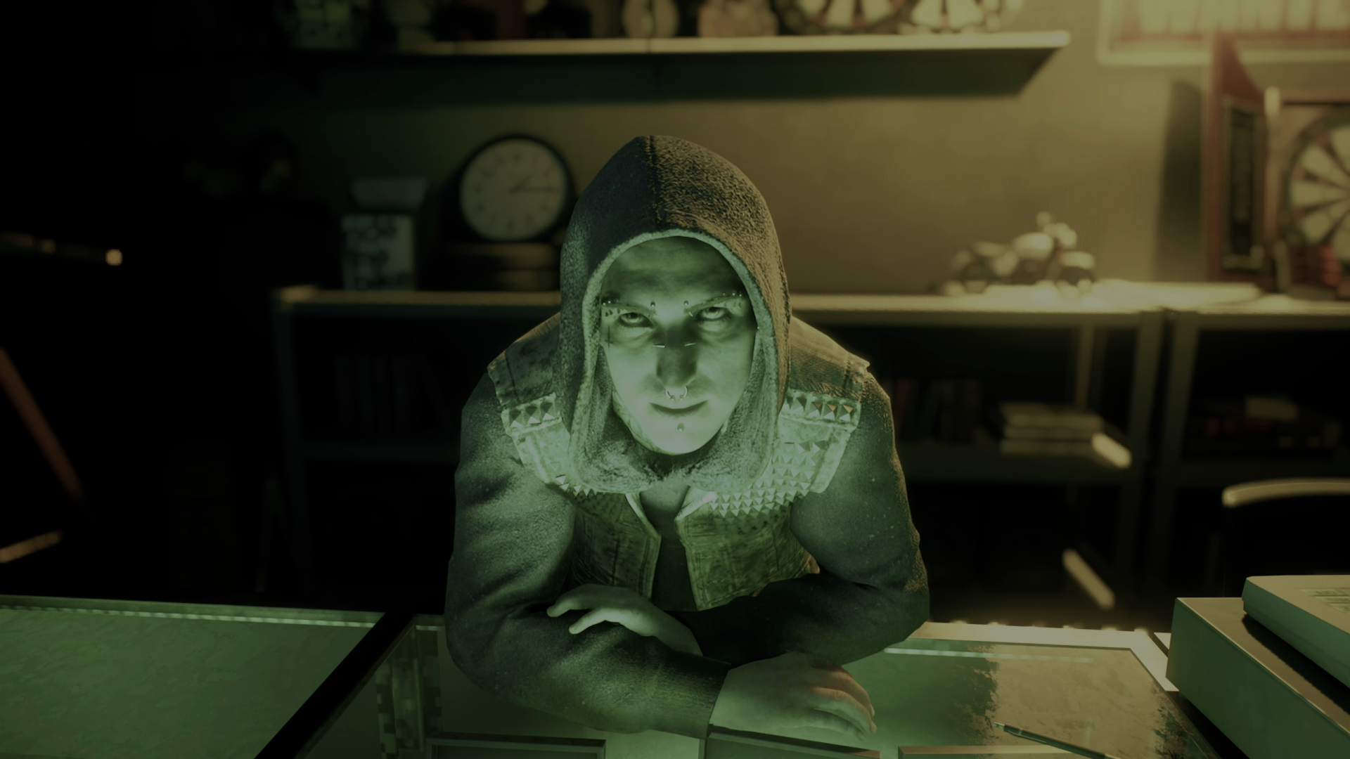 Niko — a young-looking male vampire wearing a hoodie with the hood pulled up over his head, a studded vest, and sporting many facial piercings — leans over his pawnshop counter to address the player in Vampire: The Masquerade Bloodlines 2. - 9