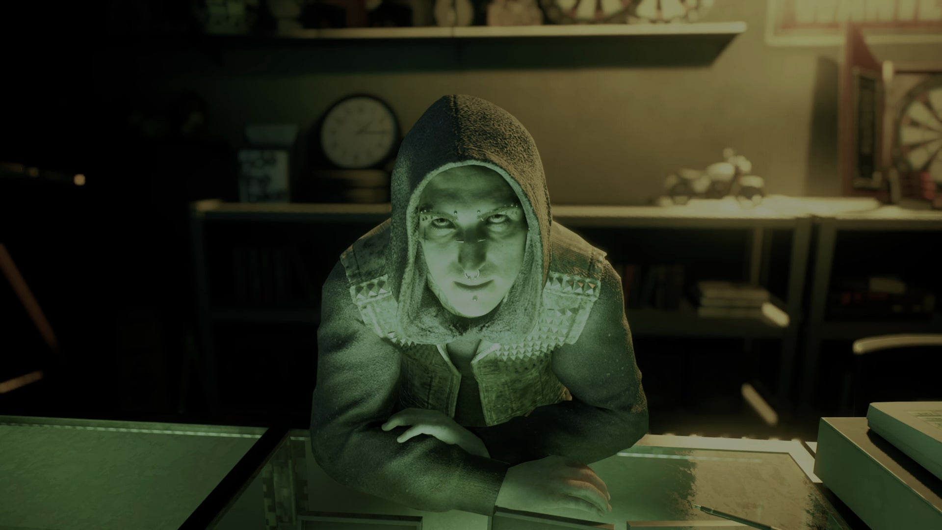 Niko — a young-looking male vampire wearing a hoodie with the hood pulled up over his head, a studded vest, and sporting many facial piercings — leans over his pawnshop counter to address the player in Vampire: The Masquerade Bloodlines 2. - 9