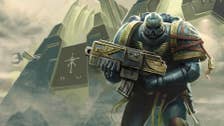 A Warhammer 40K Space Marine hodling a gun, stood in front of some kind of temple, looking into the camera.