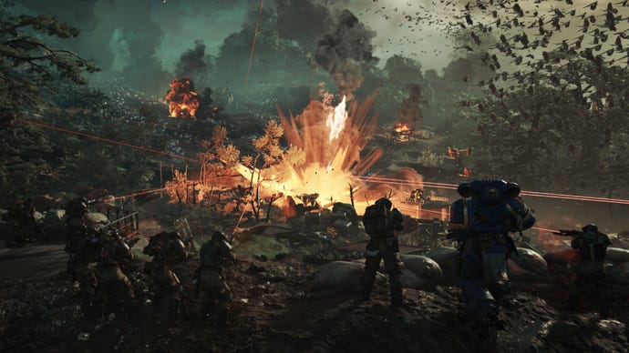 A group of soldiers stand with Titus, firing into the explosions of a battlefield.