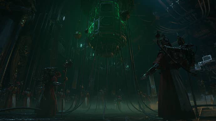 The priestly worshipers of 40K raise their arms to a machine in the centre of a room.