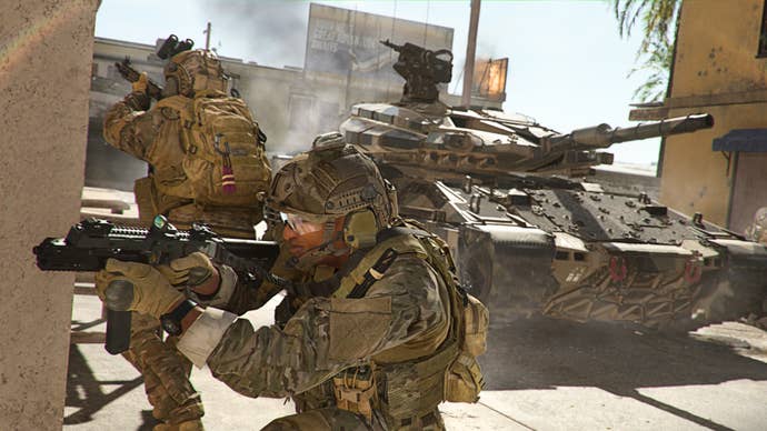 A tank in Warzone 2.0 is flanked by two soldiers aiming off-screen.