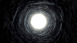 A photograph from the bottom of a well looking up towards the light. It's all darkness apart from the top of the well and some semblance of bricks on it.