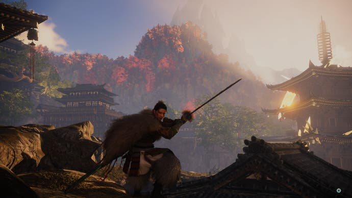 Wild Hearts review - player character poses with katana drawn in front of a distant red, orange and green mountain forest in golden sunlight