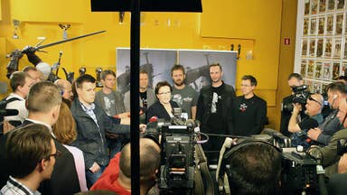 A crowded atrium of a game development studio showing TV cameras pointing at a smartly dressed lady - the then Prime Minister of Poland - while press watch on.