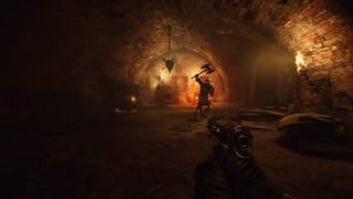 In a moody dungeon, a character wielding a weapon of some kind stands off in the distance, lit from behind with torchlight.