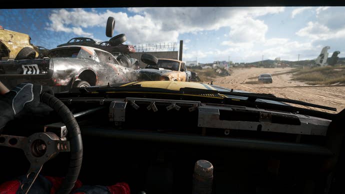 Wreckfest screenshot; you see a dusty road from the inside of a minimalist derby car. A steering wheel is on the left.