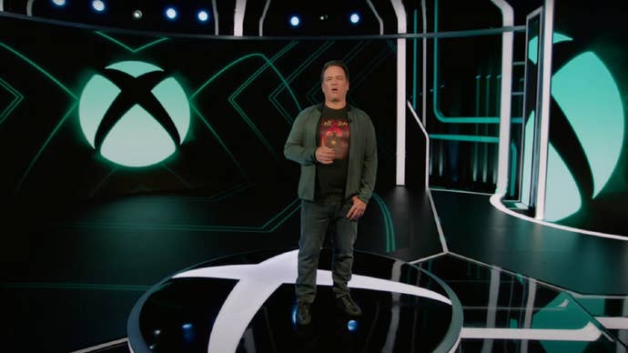 Phil Spencer stands in front of the Xbox logo.