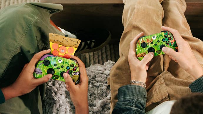 Two people holding a different version of the Teenage Mutant Ninja Turtle pizza-scented Xbox controllers
