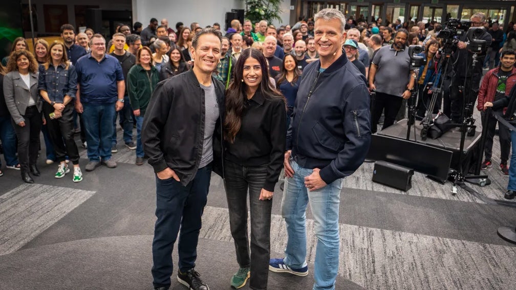Xbox trio Phil Spencer, Asha Sharma, and Matt Booty stand in a line before a large assembled crowd behind them.